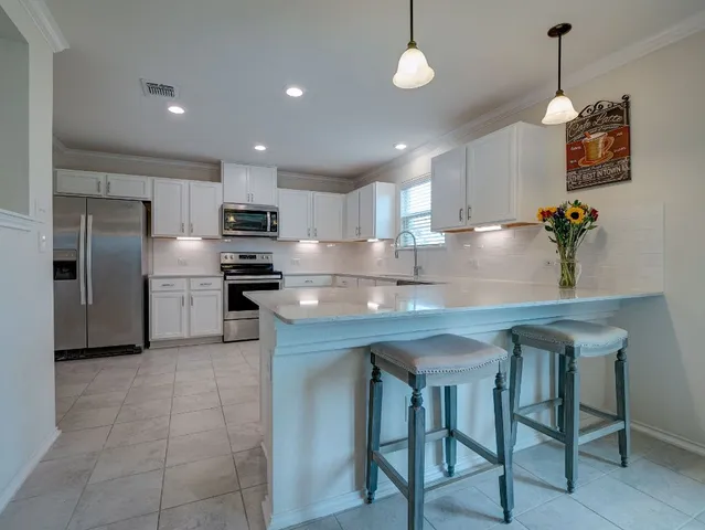 a kitchen with stainless steel appliances granite countertop a sink a stove a refrigerator with a dining table and chairs