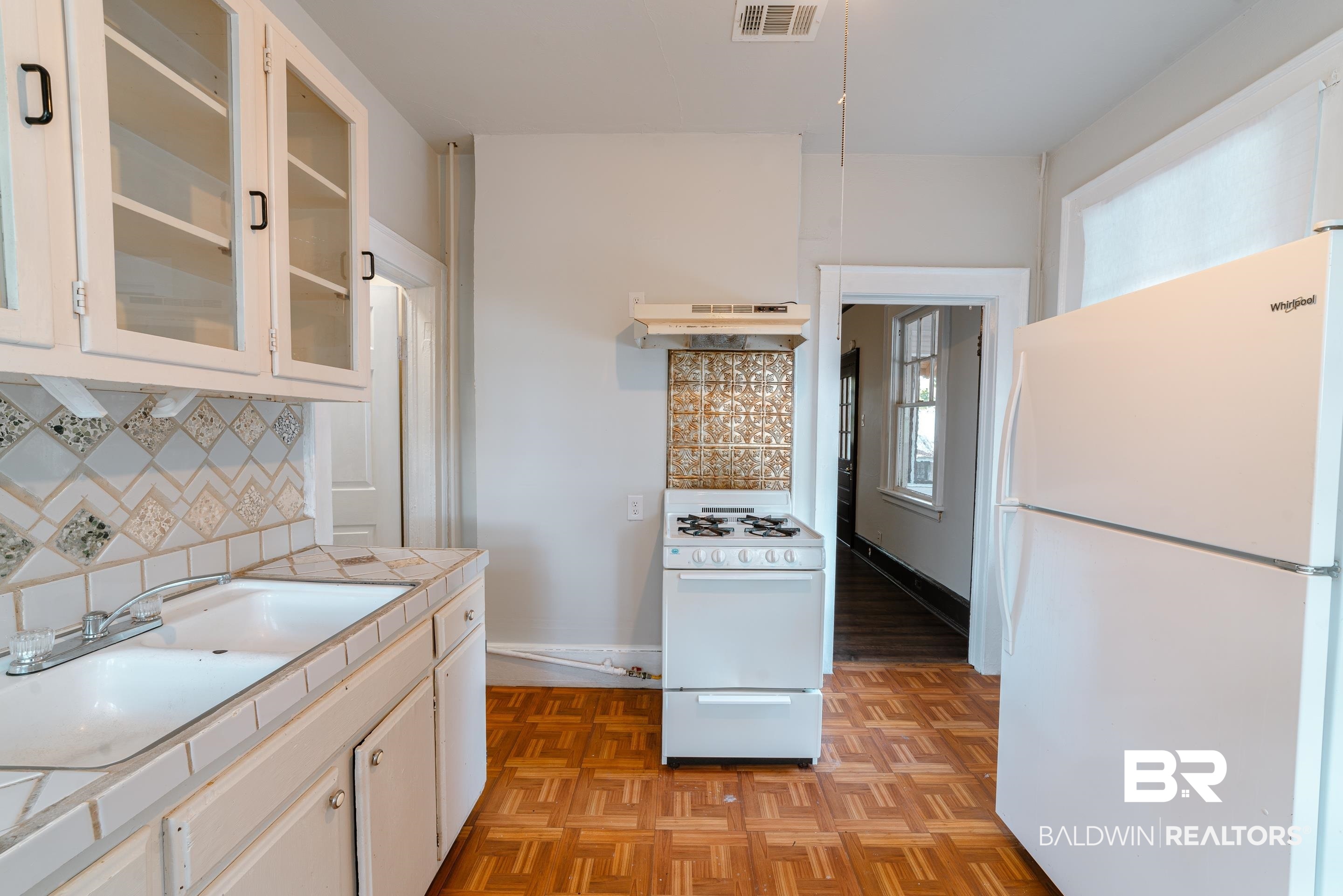 312 1st Street Mobile, AL 36611 - Photo 11 of 29 Kitchen with white appliances, backsplash, light parquet floors, and white cabinets