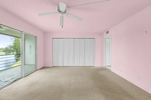 an empty room with a ceiling fan and windows