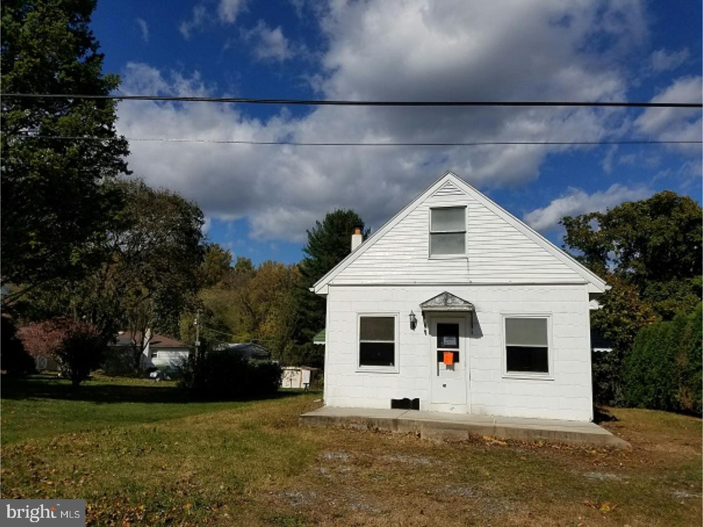 a view of a white house next to a yard with big trees