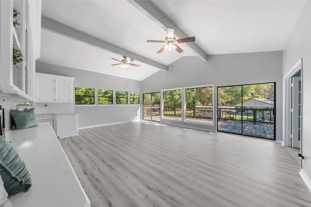 a view of an empty room with a window and wooden floor