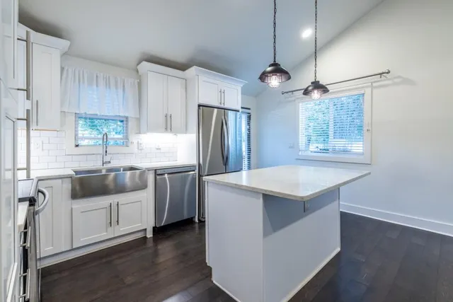 a kitchen with kitchen island granite countertop a sink a counter space appliances and cabinets