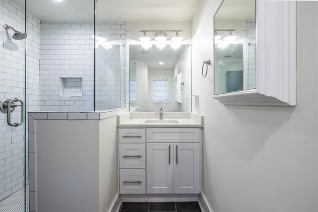 a bathroom with a granite countertop sink a mirror and a shower