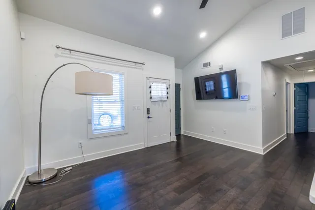 an empty room with wooden floor mirror and windows