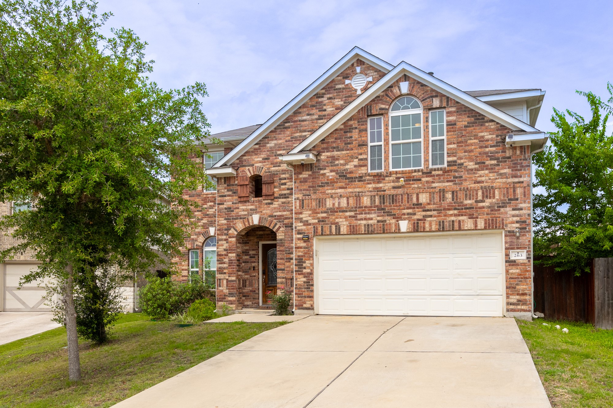 a front view of a house with a garden and trees