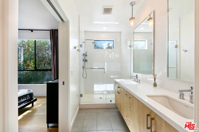 a spacious bathroom with a double vanity sink a mirror and a shower