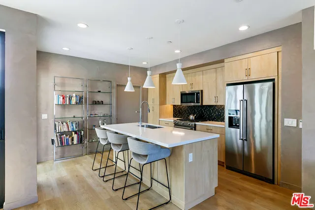 a kitchen with stainless steel appliances granite countertop a refrigerator a stove a sink a dining table and chairs