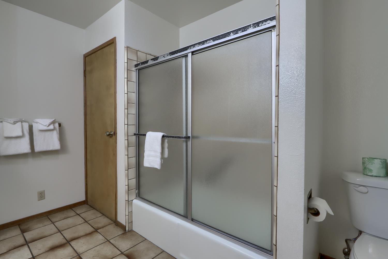 8041 Chilnualna Falls Road Wawona, CA 95389 - Photo 16 of 46 a bathroom with a glass shower door