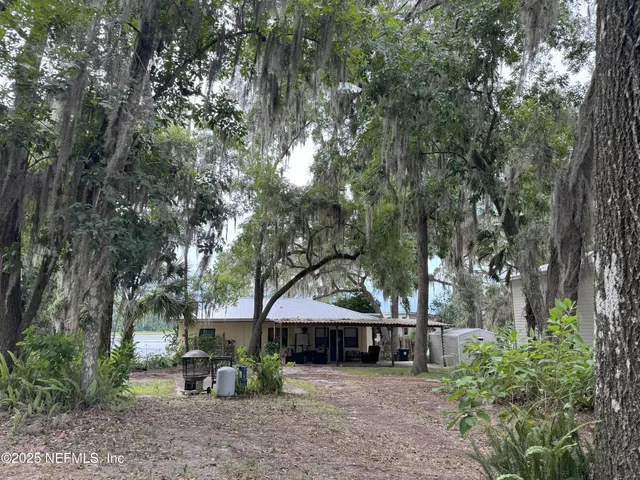 a view of a house with large trees and sitting area
