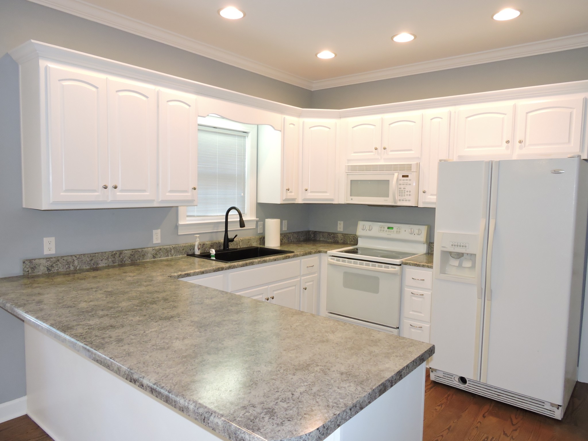 187 Oak Hollow Road Manchester, TN 37355 - Photo 5 of 25 a kitchen with a refrigerator a stove a sink and white cabinets with wooden floor