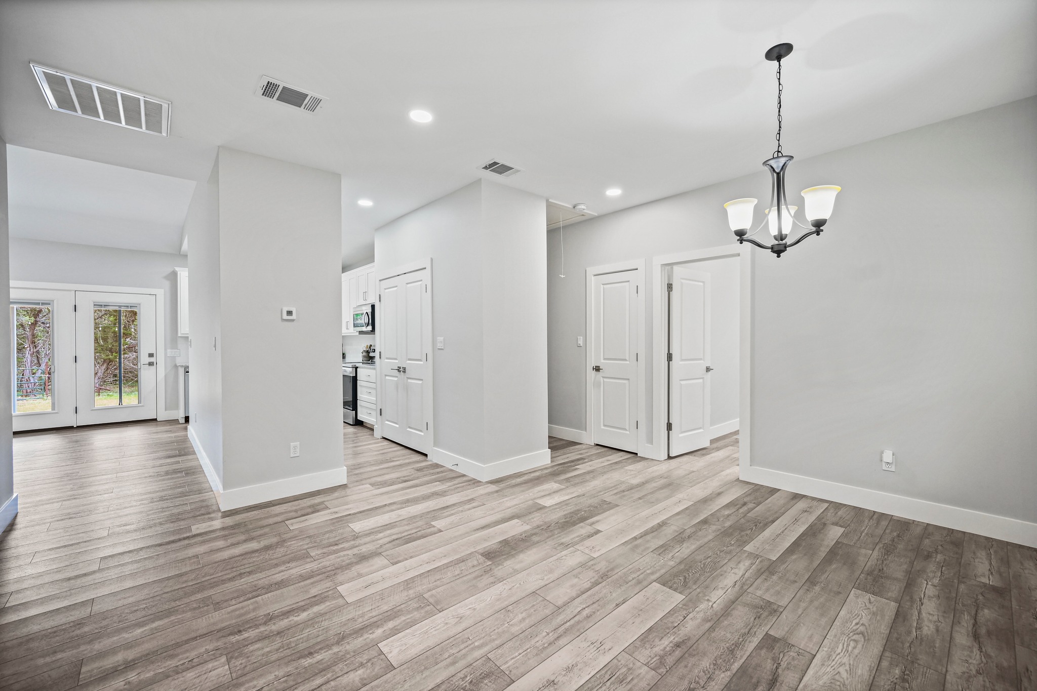 231 North Rainbow Ranch Road Wimberley, TX 78676 - Photo 7 of 40 Natural wood flooring complements this open-concept layout, offering a versatile space for living and dining.