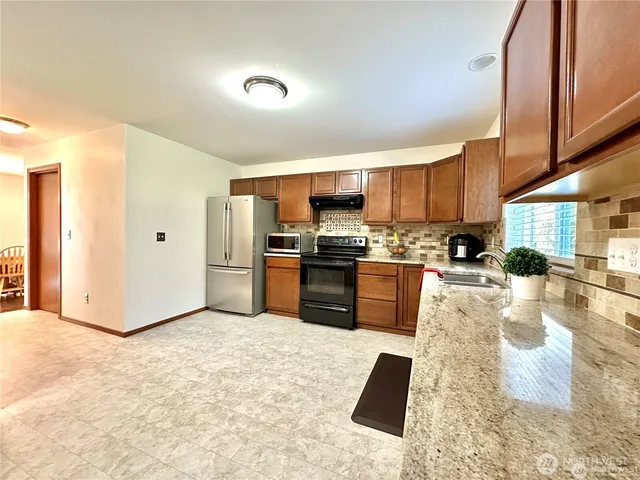 a kitchen with granite countertop a refrigerator and a sink