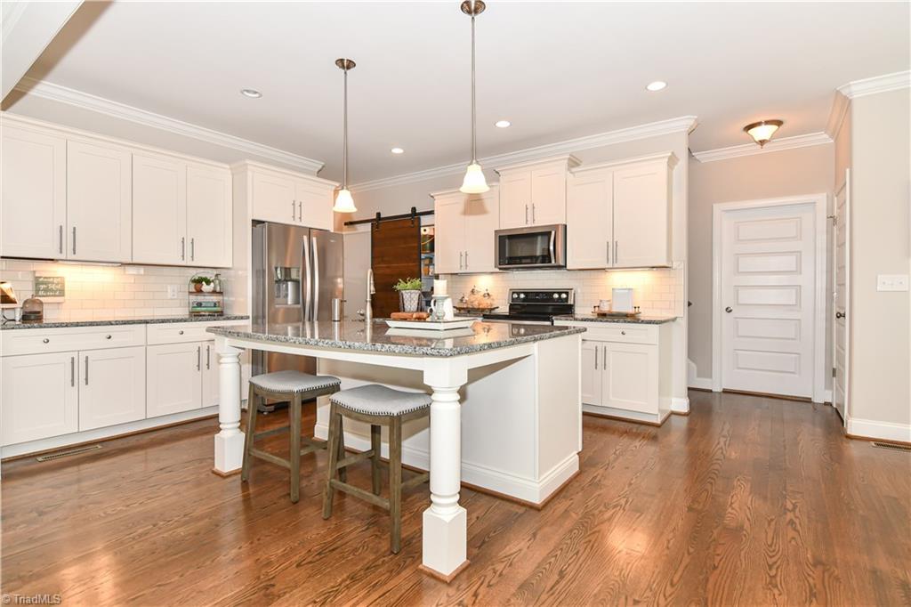 7434 Princess Ann Court Rural Hall, NC 27045 - Photo 11 of 30 Lots of cabinets, work island, granite counters, SS apps, and Barn door panty make this a magnificent cooks kitchen.