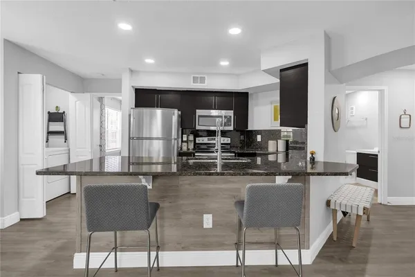 a kitchen with stainless steel appliances kitchen island granite countertop a refrigerator and microwave