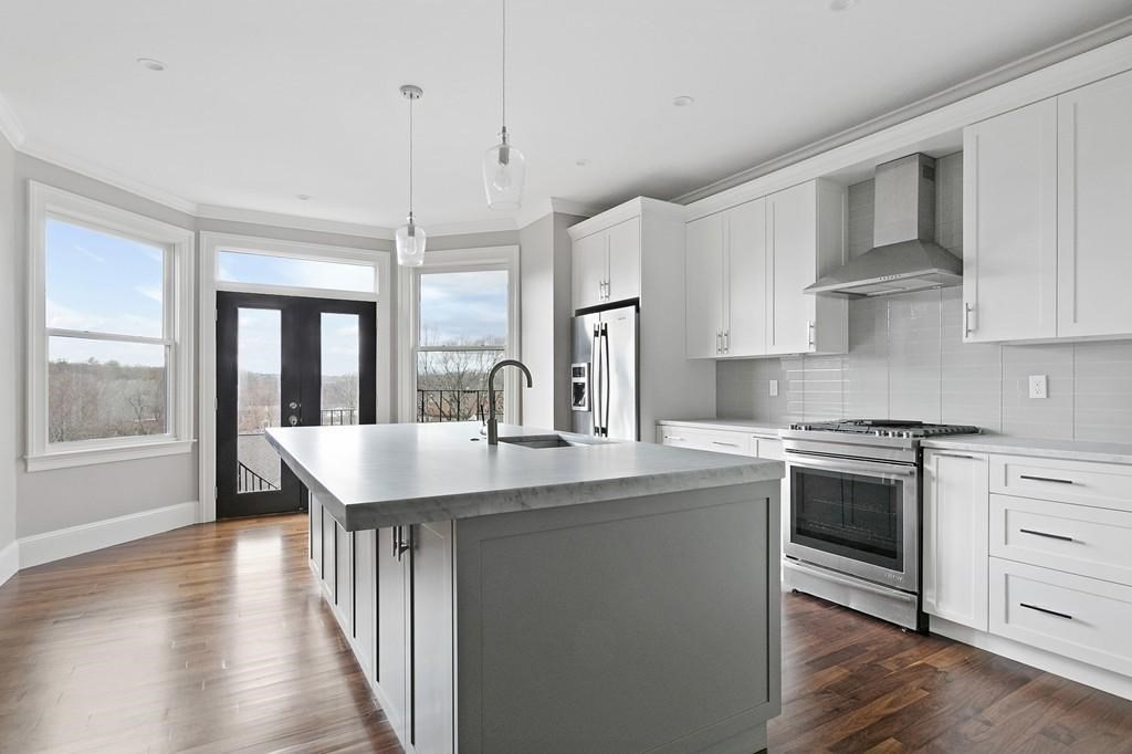 a kitchen with stainless steel appliances granite countertop a stove a sink and a refrigerator with white cabinets