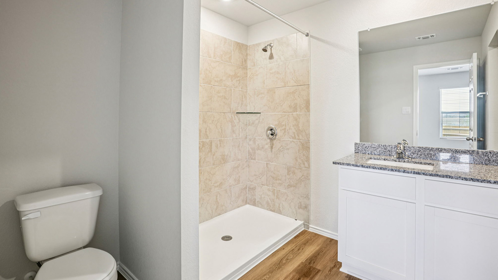 148 Wyatt Way Jarrell, TX 76537 - Photo 19 of 33 Bathroom featuring a tiled standing shower with chrome fixtures, a single vanity with a granite countertop and undermount sink, a large wall-mounted mirror, and wood-finish flooring
