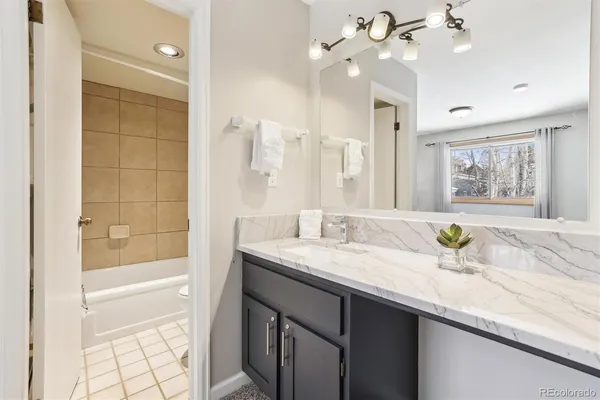 a bathroom with a granite countertop sink a toilet a mirror and shower