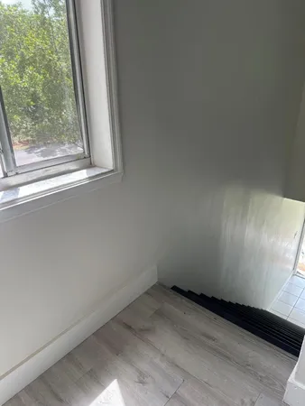 a view of a small space with wooden floor and a window