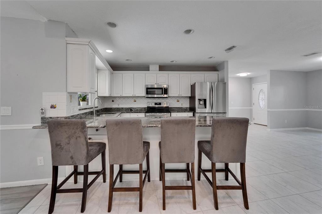 9403 Bellhaven Street Temple Terrace, FL 33637 - Photo 13 of 59 a kitchen with kitchen island granite countertop a dining table chairs and white cabinets