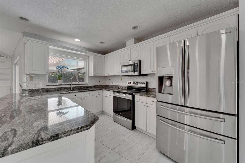 9403 Bellhaven Street Temple Terrace, FL 33637 - Photo 14 of 59 a kitchen with kitchen island granite countertop white cabinets and refrigerator