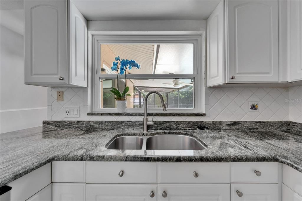 9403 Bellhaven Street Temple Terrace, FL 33637 - Photo 17 of 59 a kitchen with granite countertop a sink a window and cabinets