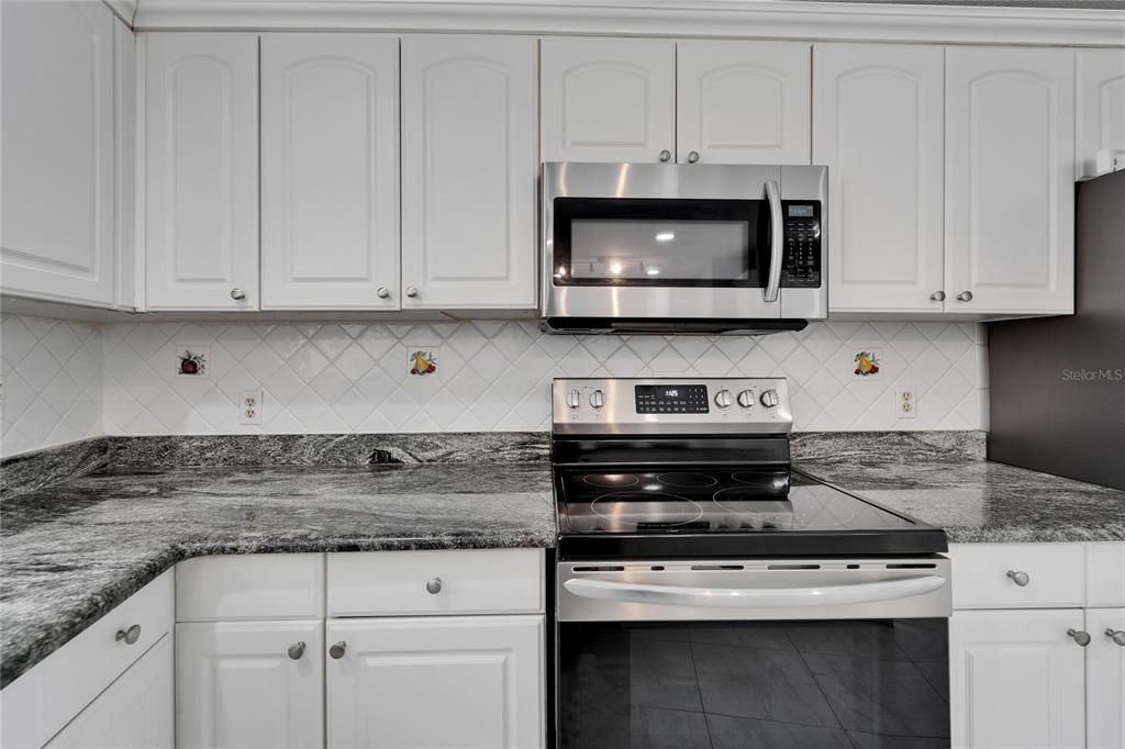 9403 Bellhaven Street Temple Terrace, FL 33637 - Photo 18 of 59 a kitchen with stainless steel appliances granite countertop white cabinets and a stove a sink