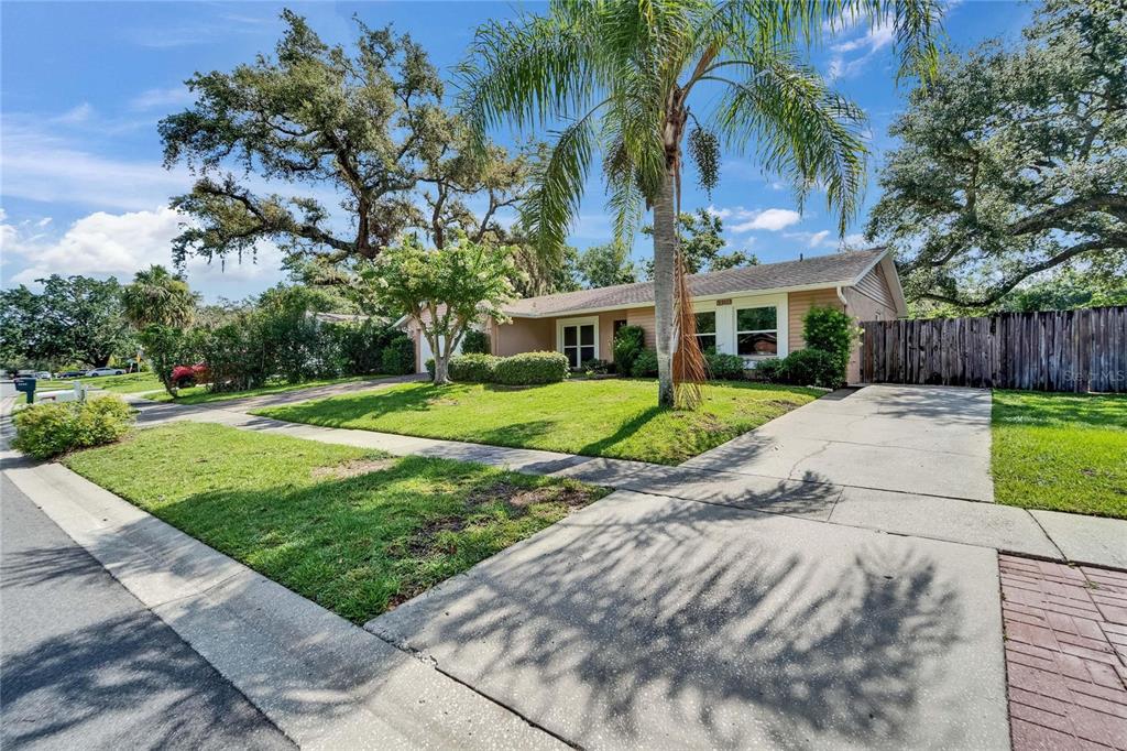 9403 Bellhaven Street Temple Terrace, FL 33637 - Photo 3 of 59 a view of a white house with a big yard and potted plants