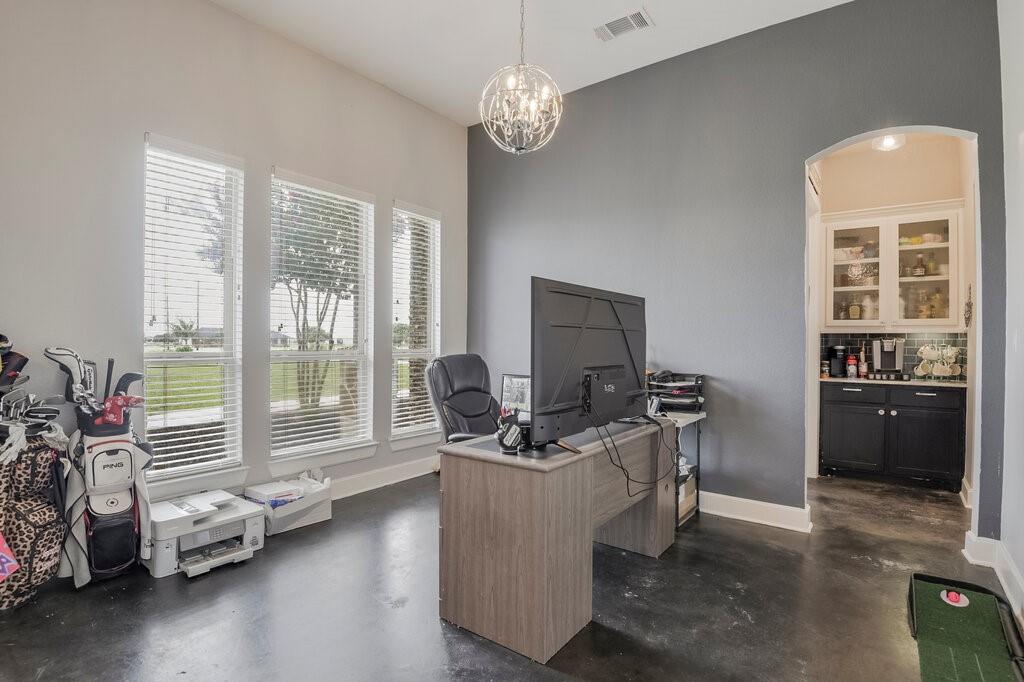 239 North Armstrong Road Venus, TX 76084 - Photo 18 of 39 Room featuring polished concrete flooring, three large windows with horizontal blinds, a contemporary chandelier, and an arched doorway leading to a built-in cabinet area