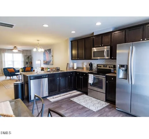 a kitchen with stainless steel appliances kitchen island granite countertop a refrigerator a sink a stove a microwave and island