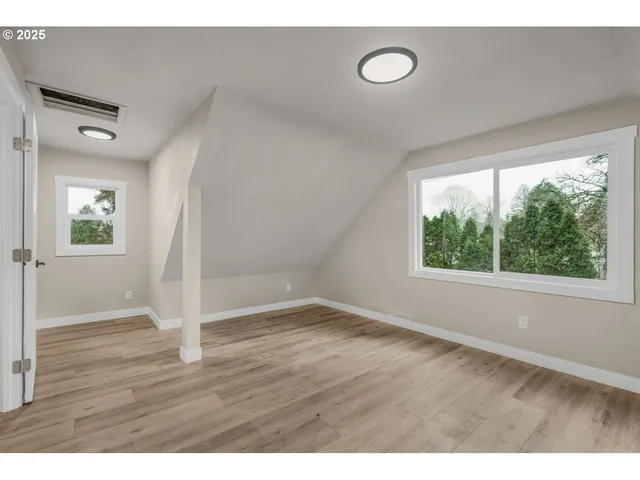 a view of an empty room with wooden floor and window