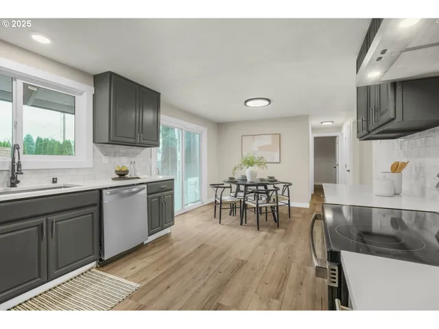 a kitchen with stainless steel appliances a dining table chairs sink and cabinets