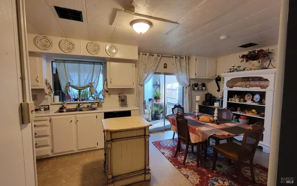 a kitchen with stainless steel appliances kitchen island granite countertop a table chairs cabinets and a sink