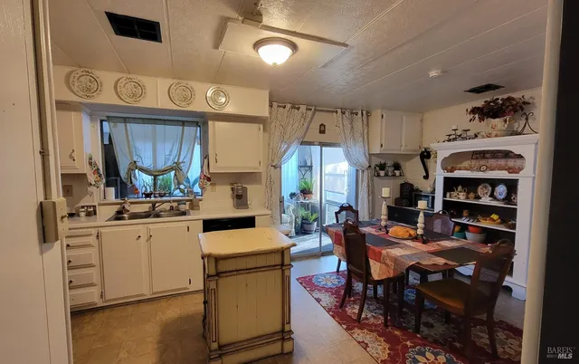 a kitchen with stainless steel appliances kitchen island granite countertop a table chairs cabinets and a sink
