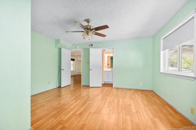 a view of empty room with wooden floor and fan