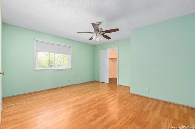 an empty room with a window and a ceiling fan