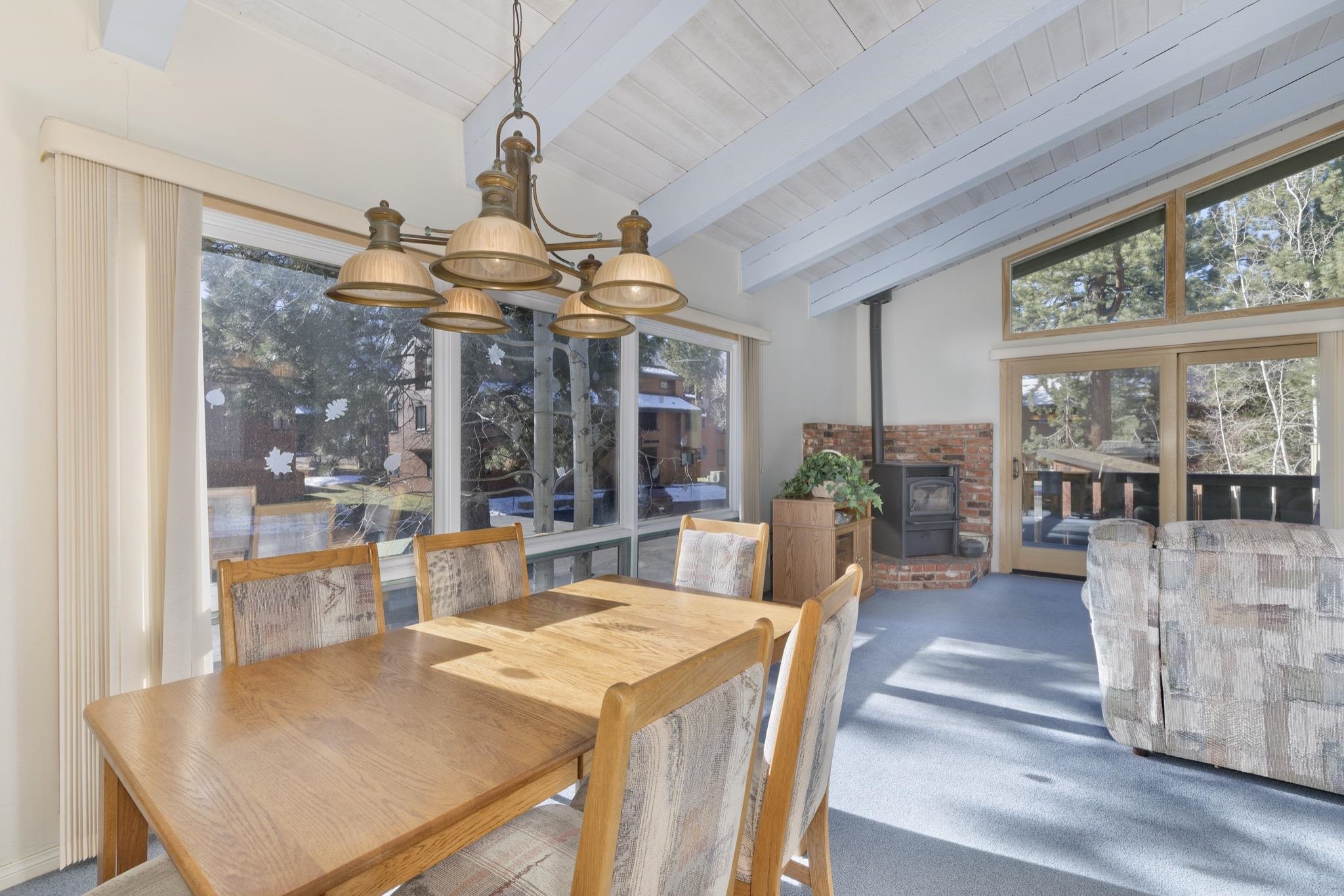 3251 Chateau Road, Unit 40 Mammoth Lakes, CA 93546 - Photo 7 of 31 Dining room featuring a wood stove, vaulted ceiling with beams, carpet, wood ceiling, and suspended lighting
