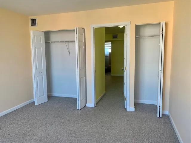 a view of an empty room with closet and a window