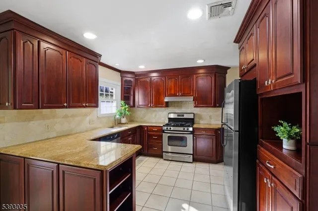 a kitchen with stainless steel appliances granite countertop wooden cabinets a stove top oven a sink and dishwasher