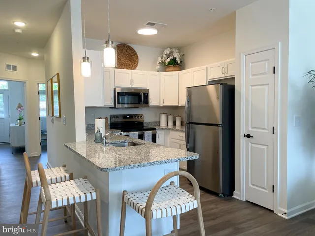 a kitchen with stainless steel appliances granite countertop a refrigerator a stove a sink a dining table and chairs