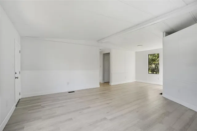 a view of an empty room with wooden floor and windows