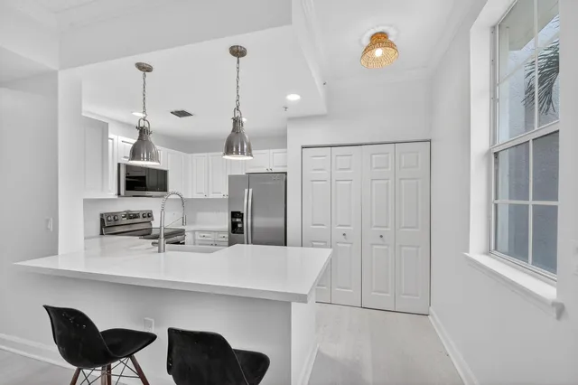 a kitchen with stainless steel appliances kitchen island granite countertop a refrigerator a sink dishwasher a dining table and chairs with wooden floor