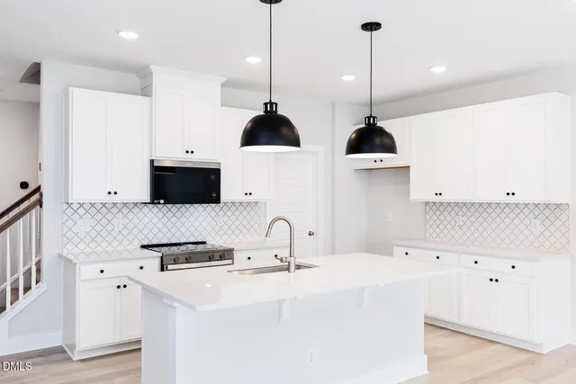 a kitchen with stainless steel appliances a sink a stove and a wooden floor