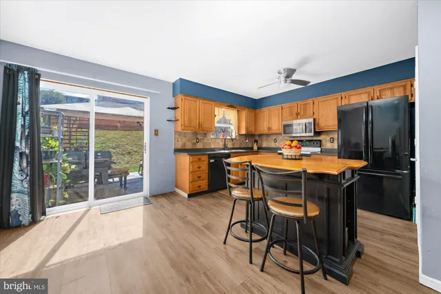 a kitchen with stainless steel appliances a table chairs refrigerator and cabinets
