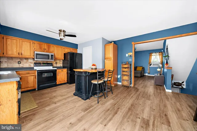 a kitchen with stainless steel appliances a stove top oven a sink dishwasher and a dining table with wooden floor