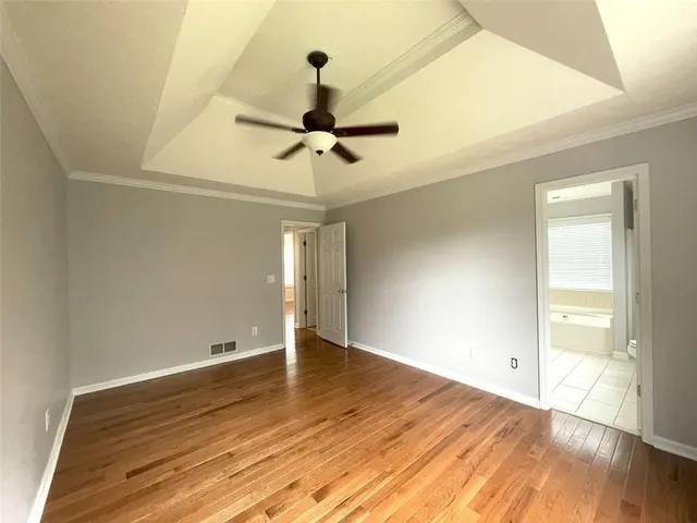 an empty room with wooden floor fan and windows