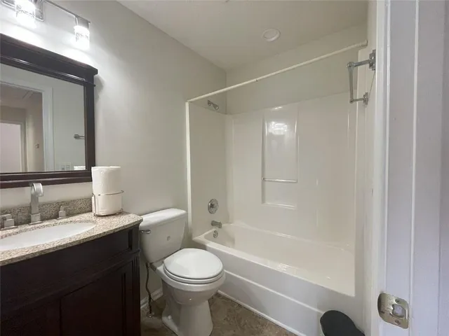 a bathroom with a granite countertop toilet a sink and a bathtub