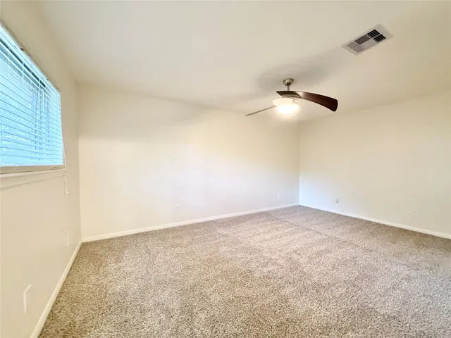 an empty room with a ceiling fan and carpet