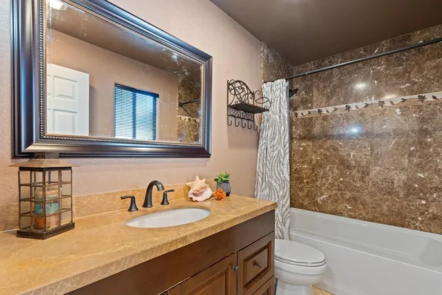 a bathroom with a granite countertop sink toilet and shower