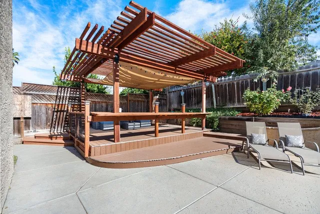 a view of a patio with a table and chairs under an umbrella with a barbeque