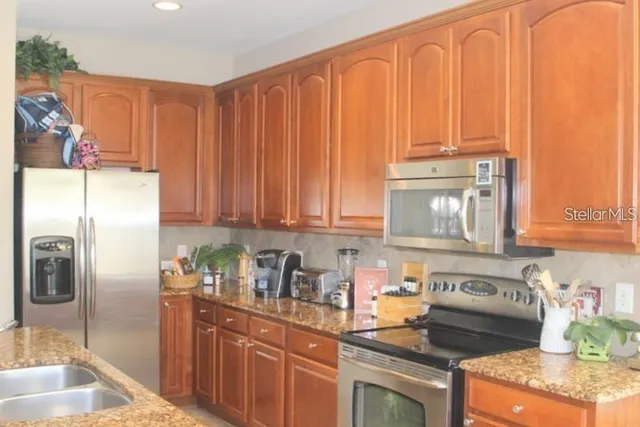 a kitchen with stainless steel appliances granite countertop a refrigerator a stove top oven a sink and dishwasher